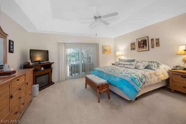 bedroom featuring light carpet, access to exterior, ceiling fan, and a raised ceiling