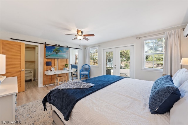 bedroom with french doors, ceiling fan, access to outside, a barn door, and light wood-type flooring