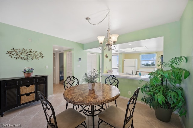 tiled dining room featuring sink and a notable chandelier