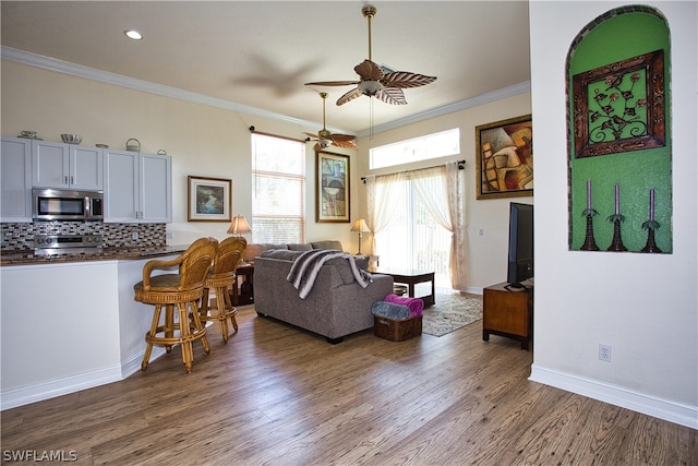 living room with crown molding, wood-type flooring, and ceiling fan