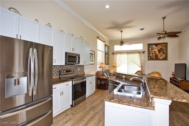 kitchen with sink, a kitchen island with sink, stainless steel appliances, tasteful backsplash, and white cabinets