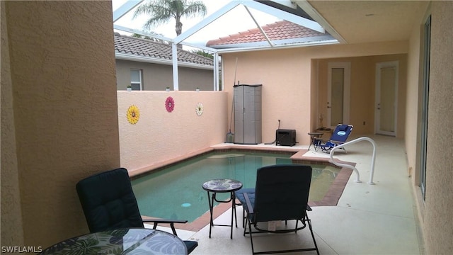 view of pool featuring glass enclosure and a patio area