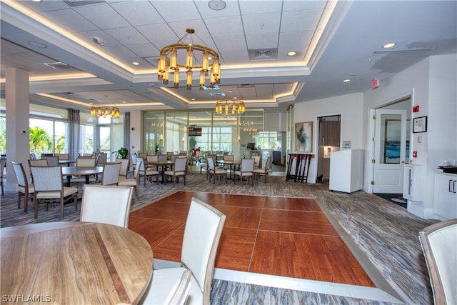 dining room with an inviting chandelier, a tray ceiling, and dark hardwood / wood-style floors