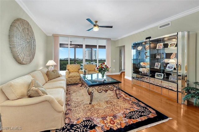 living room with ceiling fan, visible vents, wood finished floors, and crown molding