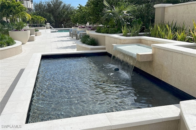 view of swimming pool with pool water feature and a patio