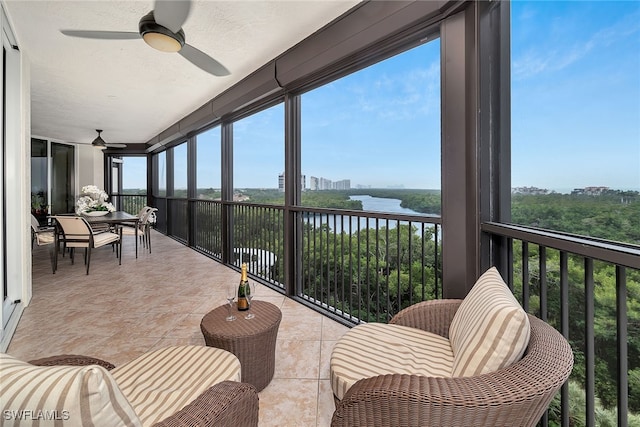 sunroom with a water view and ceiling fan