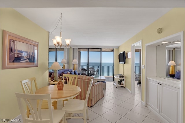 tiled dining space with a water view, a chandelier, and a wall of windows