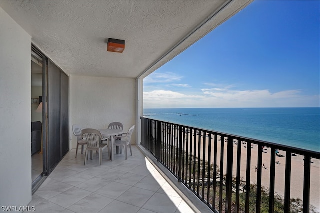 balcony featuring a view of the beach and a water view