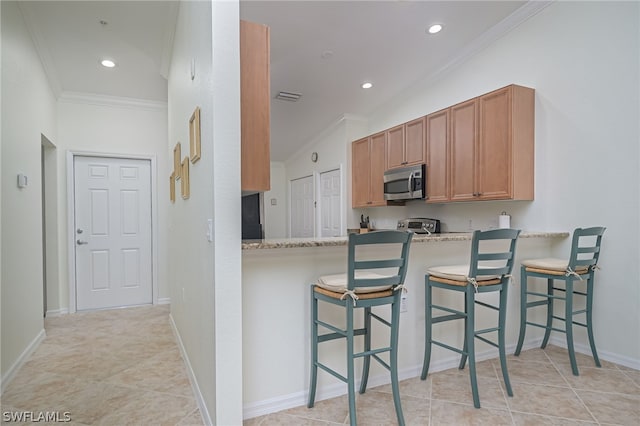 kitchen featuring a kitchen breakfast bar, light tile flooring, ornamental molding, kitchen peninsula, and light stone counters