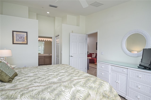 bedroom featuring ceiling fan, a towering ceiling, connected bathroom, and light tile floors