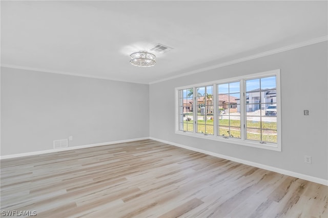 empty room featuring a notable chandelier, crown molding, and light hardwood / wood-style floors