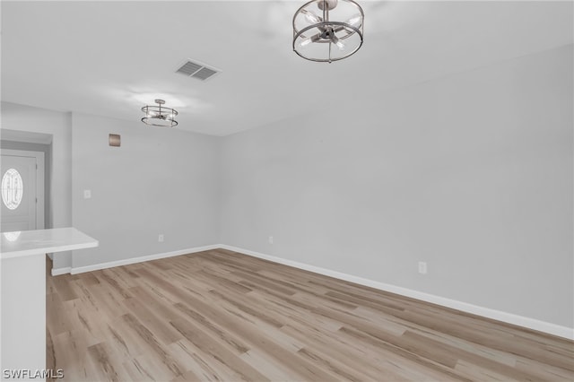 unfurnished room with an inviting chandelier and light wood-type flooring