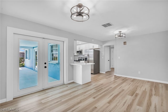 doorway featuring a notable chandelier, french doors, and light wood-type flooring