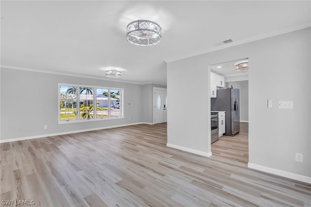 spare room featuring an inviting chandelier, ornamental molding, and light hardwood / wood-style floors