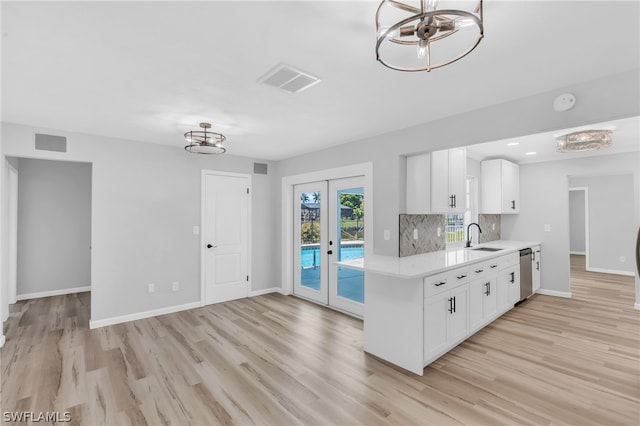 kitchen with stainless steel dishwasher, white cabinets, backsplash, light hardwood / wood-style floors, and french doors