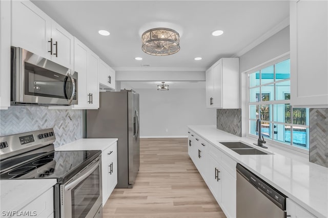 kitchen featuring white cabinetry, appliances with stainless steel finishes, sink, light wood-type flooring, and tasteful backsplash