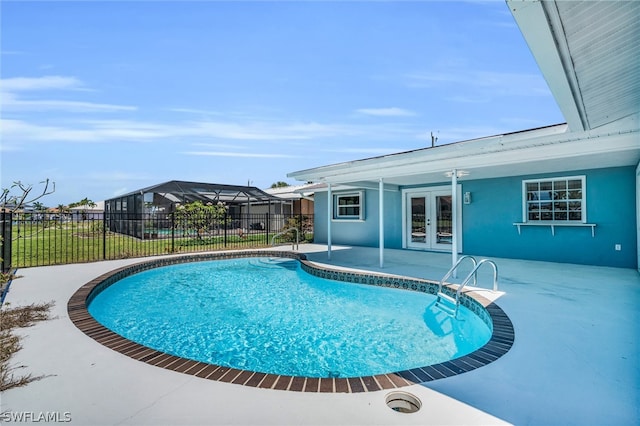 view of pool with glass enclosure, a patio area, and french doors