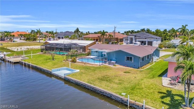 rear view of house featuring a lanai, a water view, a patio area, and a yard