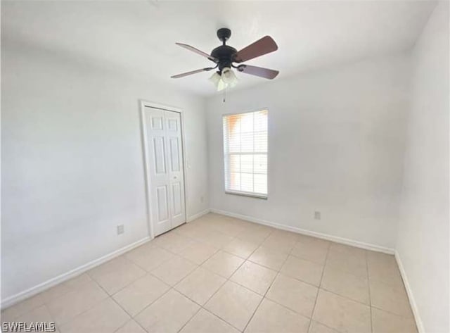 spare room with ceiling fan and light tile floors