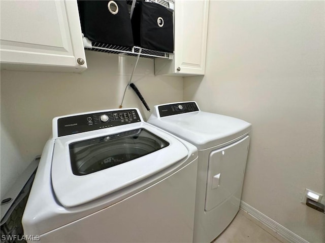 clothes washing area with washer and clothes dryer and cabinets