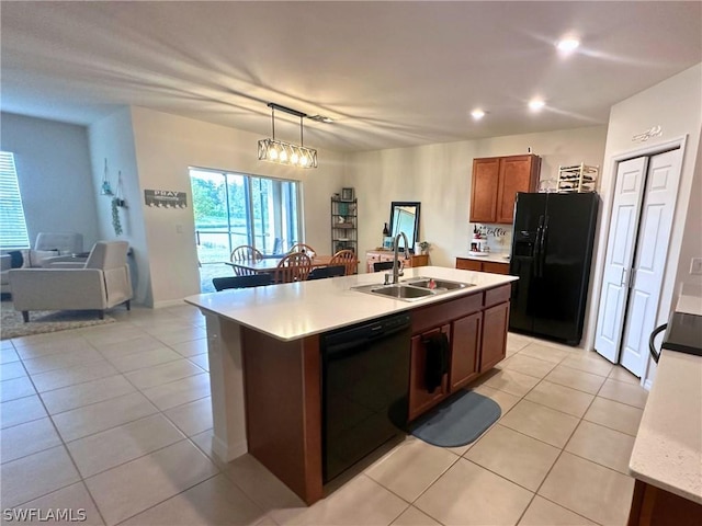 kitchen with black appliances, light tile patterned floors, an island with sink, hanging light fixtures, and sink