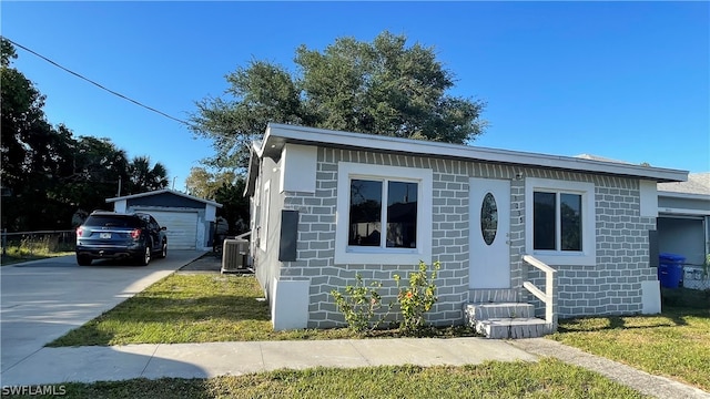 view of front of home with central AC, an outdoor structure, a garage, and a front yard