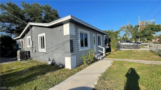 view of side of property featuring a lawn and central AC unit