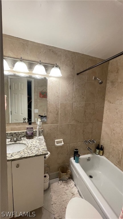 full bathroom with tiled shower / bath, tile walls, vanity, tile flooring, and toilet