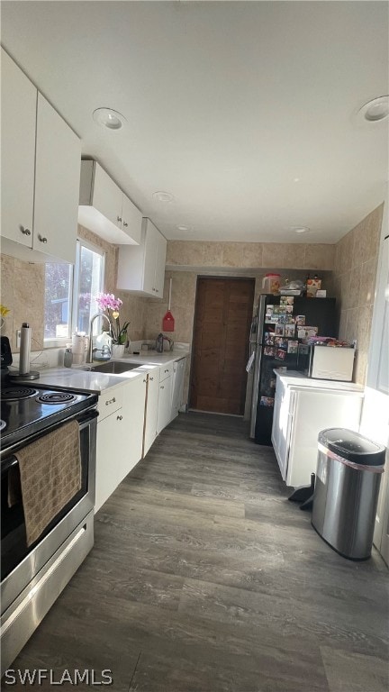 kitchen featuring sink, white cabinetry, stainless steel range with electric cooktop, dark hardwood / wood-style floors, and washer / clothes dryer