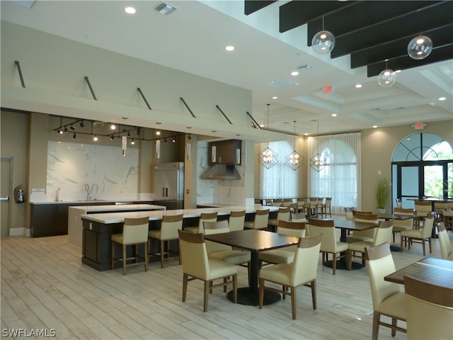 dining area featuring sink, light wood-type flooring, and beam ceiling