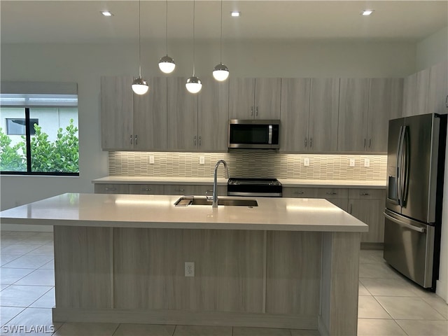 kitchen featuring stainless steel appliances, backsplash, a center island with sink, sink, and light tile floors