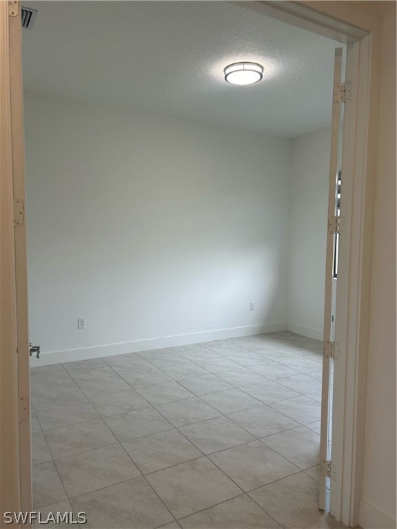 tiled spare room with a textured ceiling