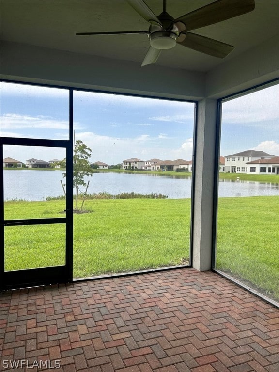 unfurnished sunroom featuring ceiling fan and a water view