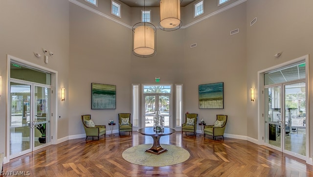 interior space with french doors, a towering ceiling, and a healthy amount of sunlight