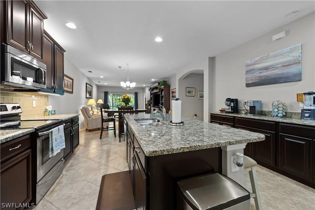 kitchen featuring a kitchen island with sink, an inviting chandelier, sink, appliances with stainless steel finishes, and tasteful backsplash