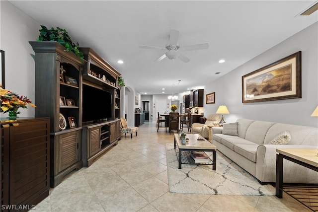 tiled living room with ceiling fan with notable chandelier