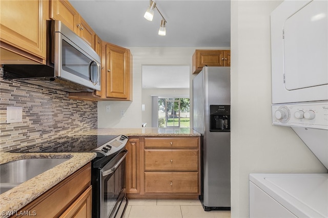 kitchen with appliances with stainless steel finishes, light stone counters, tasteful backsplash, track lighting, and light tile flooring