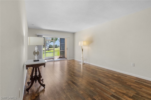 unfurnished room with dark hardwood / wood-style flooring and a textured ceiling