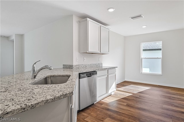 kitchen with light stone countertops, stainless steel dishwasher, wood-type flooring, white cabinets, and sink