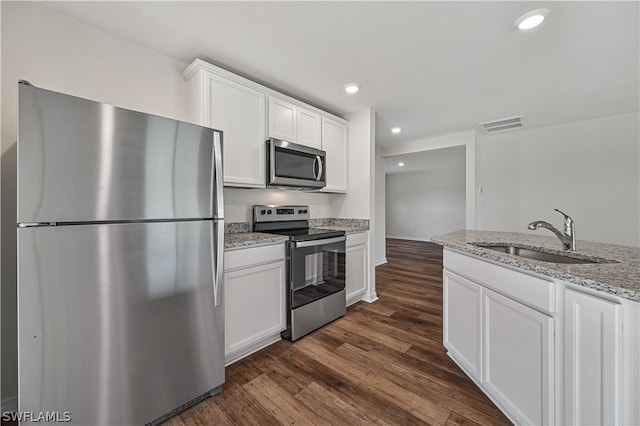 kitchen featuring dark hardwood / wood-style flooring, stainless steel appliances, white cabinets, light stone counters, and sink