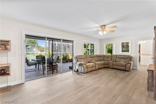 living room featuring light hardwood / wood-style flooring, ceiling fan, and plenty of natural light