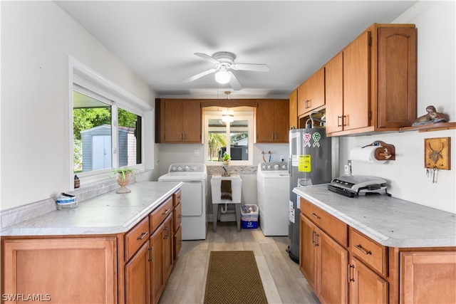 kitchen featuring a healthy amount of sunlight, ceiling fan, light hardwood / wood-style floors, and washing machine and clothes dryer