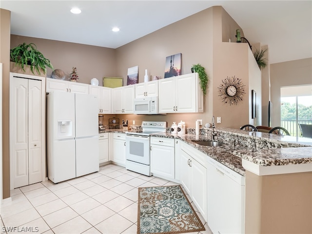 kitchen featuring white cabinets, sink, white appliances, kitchen peninsula, and dark stone countertops