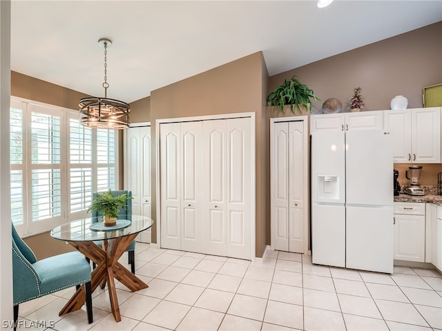 kitchen with white fridge with ice dispenser, white cabinets, and light tile floors