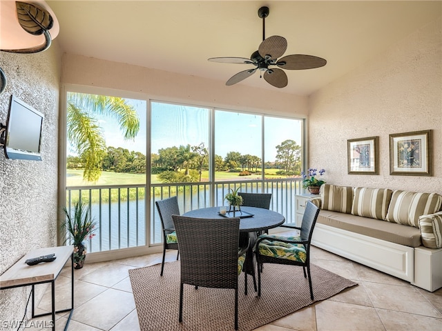 sunroom / solarium with ceiling fan and a water view