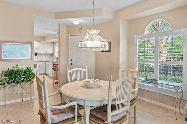 tiled dining room with a notable chandelier and sink