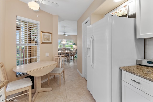 kitchen featuring light tile patterned flooring, white refrigerator with ice dispenser, white cabinetry, stone counters, and ceiling fan