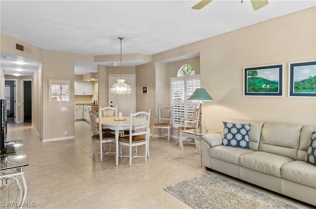 tiled living room with ceiling fan with notable chandelier