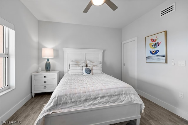 bedroom featuring ceiling fan, dark wood-type flooring, and multiple windows