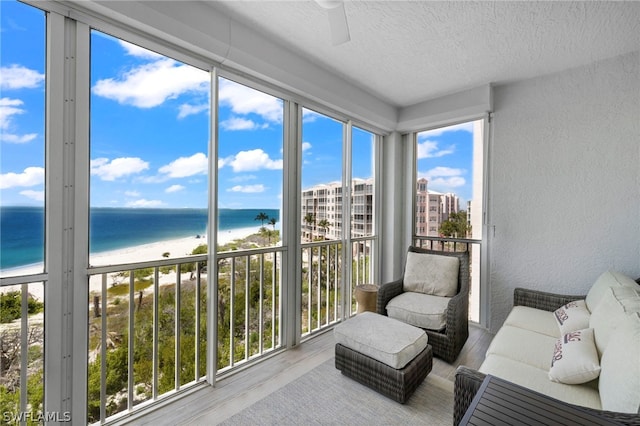 sunroom / solarium featuring a water view, plenty of natural light, and a beach view